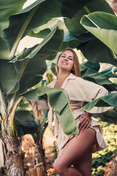 Gyönyörű nő a dzsungelben. Üdülőhely vagy hotel trópusi fákkal és növényekkel. Egy nő banánlevéllel. Egy lány az esőerdőben nyaral. Szelektív fókusz - Fotó, kép