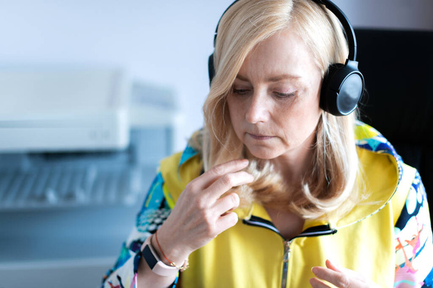 Крупним планом портрет зосередженої жінки середнього віку в навушниках, яка дивиться вебінар на офісному комп'ютері
 - Фото, зображення