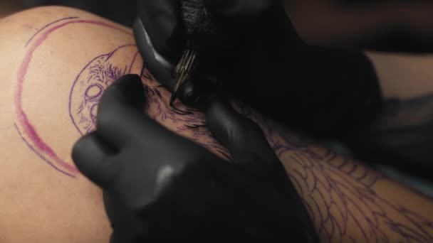 Közelkép egy tetováló művészről, aki az ügyfél karjára rajzol. Lövés RED hélium kamerával 8K-ban.   - Felvétel, videó