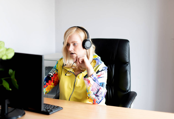 Portret poważnej kobiety w średnim wieku noszącej słuchawki oglądającej webinarium przy komputerze biurowym - Zdjęcie, obraz