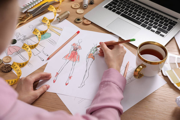 Fashion designer drawing sketch at wooden table, closeup - Foto, Imagen