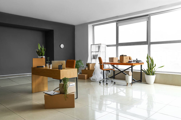 Cardboard boxes with belongings and furniture in interior of office on moving day - Photo, Image