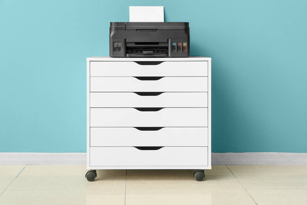 Impressora moderna no peito das gavetas perto da parede azul no interior do quarto - Foto, Imagem