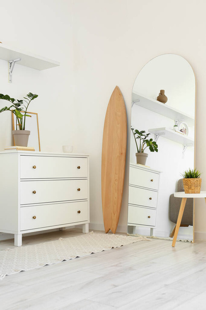 Interior de la sala de estar ligera con tabla de surf de madera, cómoda y espejo - Foto, Imagen