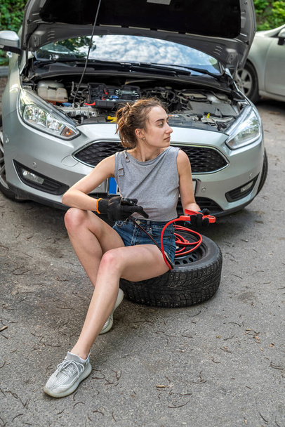 woman holding  jumper cable for recharge the battery car for repairing broken car. service at outdoor - Photo, image