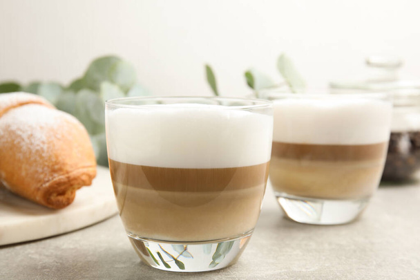 Delicious latte macchiato and croissant on light grey table - Valokuva, kuva