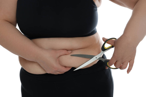 Obese woman with scissors on white background, closeup. Weight loss surgery - Zdjęcie, obraz