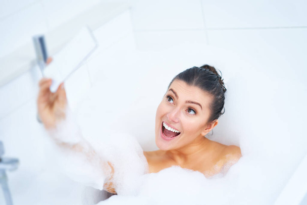 Young nice brunette woman having bath in bathtub - Photo, Image