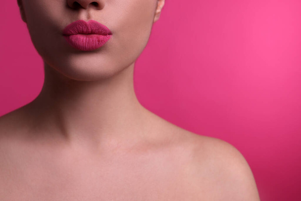 Closeup view of beautiful woman puckering lips for kiss on pink background - Photo, image