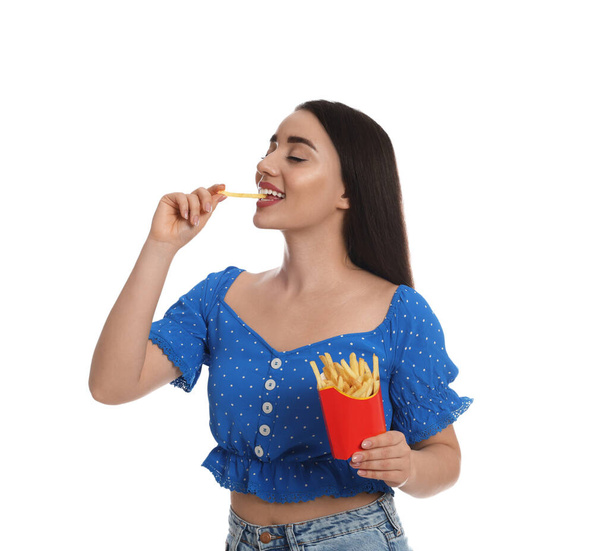 Krásná mladá žena jíst hranolky na bílém pozadí - Fotografie, Obrázek