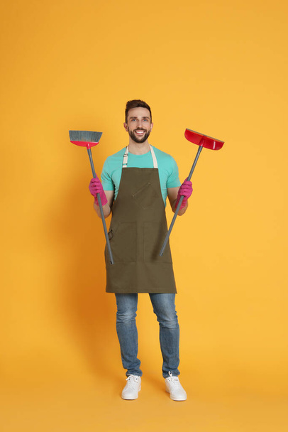 Man with broom and dustpan on orange background - Zdjęcie, obraz