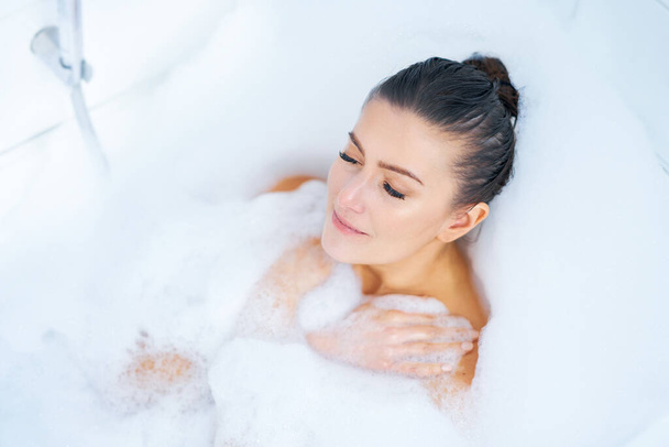 Jovem mulher morena agradável tendo banho na banheira - Foto, Imagem