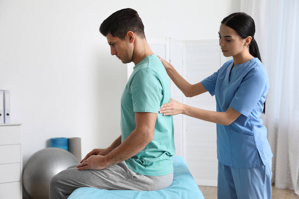 Orthopedist examining man's back in clinic. Scoliosis treatment - Фото, зображення