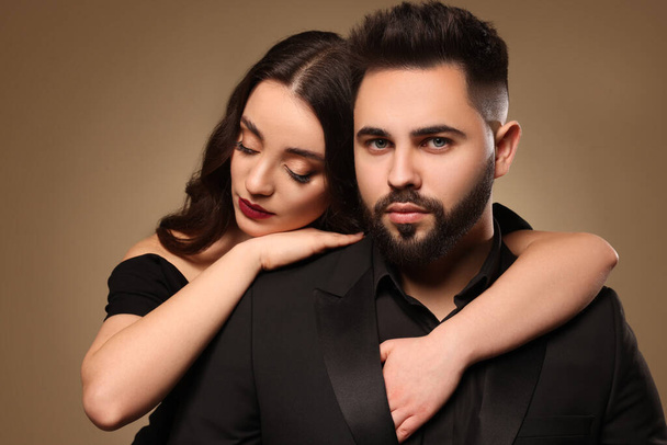 Handsome bearded man with sexy lady on light brown background - Foto, afbeelding