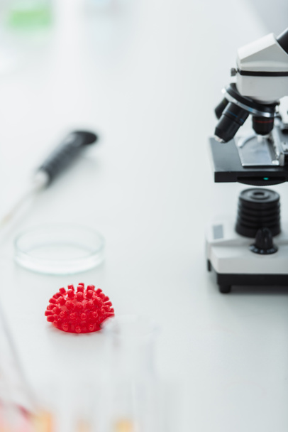 modello di batterio coronavirus rosso e microscopio sfocato in laboratorio biologico - Foto, immagini