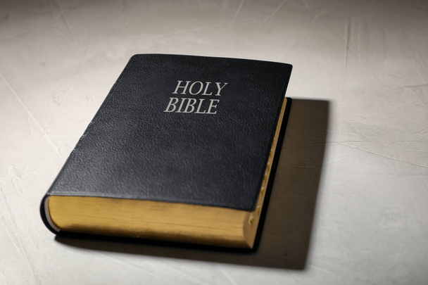 Antigua Biblia de tapa dura sobre mesa gris. Libro religioso - Foto, imagen