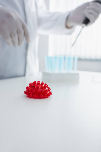 selektiivinen painopiste punainen koronavirus bakteeri malli lähellä rajattu tiedemies hämärtynyt tausta - Valokuva, kuva