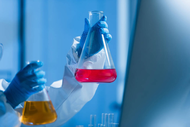 flasks with colorful liquid in hands of cropped scientist in laboratory - Photo, Image