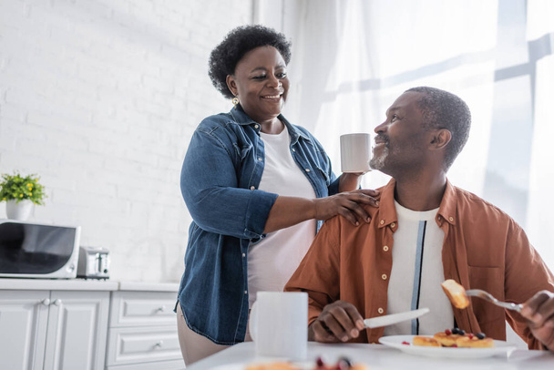 старший африканский американец завтракает и смотрит на счастливую жену - Фото, изображение
