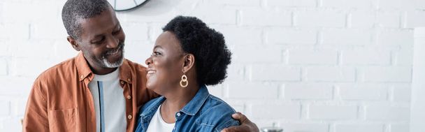 feliz homem africano sênior americano olhando para a esposa na cozinha, banner - Foto, Imagem