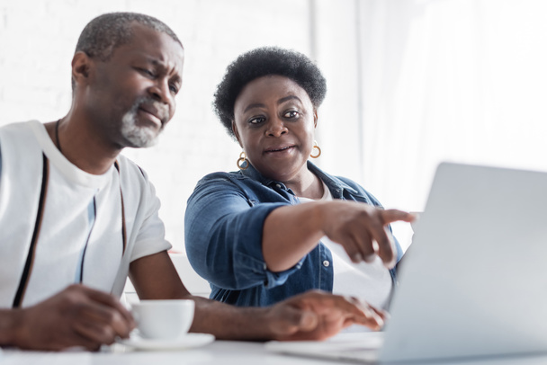retired african american woman pointing at laptop near husband  - Photo, image