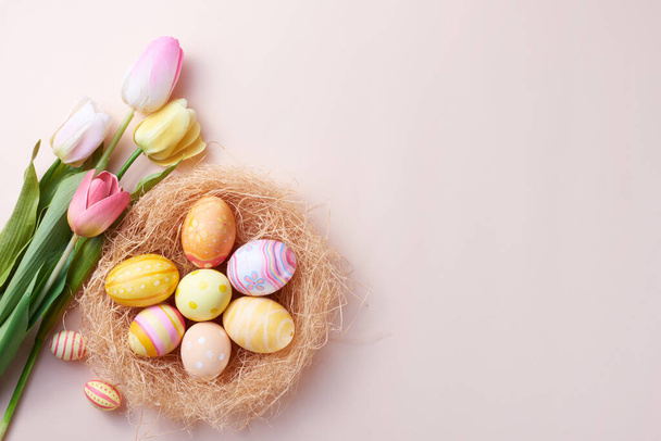 Happy Easter day colorful eggs in nest and flower on paper background with copy space. - Photo, image