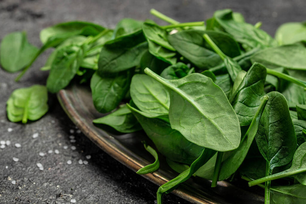Close up Spinach. Raw organic fresh baby spinach leaves in a metal bowl on dark background. Food recipe background., top view. - Foto, Bild