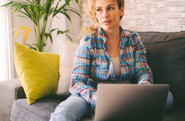 Ruhige und selbstbewusste erwachsene Frauenporträt zu Hause arbeiten auf modernen Laptop-Computer. Sitzende Frauen genießen Freizeitaktivitäten in Innenräumen. Soziale Medien und Online-Jobkonzept - Foto, Bild
