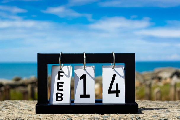 Φεβ 14 ημερολόγιο ημερομηνία κείμενο σε ξύλινο πλαίσιο με θολή φόντο του ωκεανού. Έννοια ημερομηνίας ημερολογίου - Φωτογραφία, εικόνα