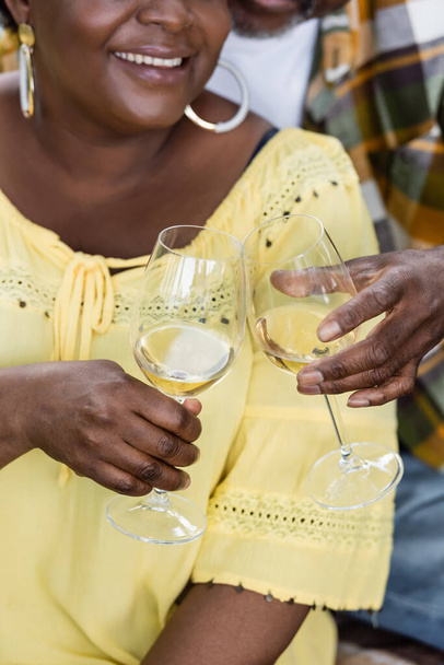 vista ritagliata di gioiosa e anziana coppia afro-americana bicchieri di vino - Foto, immagini
