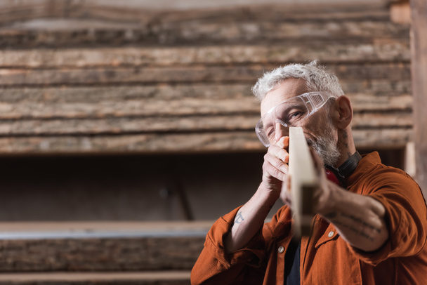 middle aged carpenter checking blurred plank in workshop - Foto, Imagen