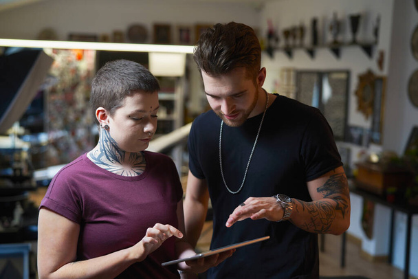 Δύο Καυκάσιοι άνθρωποι με συζήτηση τατουάζ για το νέο έργο - Φωτογραφία, εικόνα