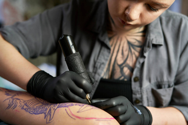 Közelkép tetováló művész rajz a kar az ügyfél - Fotó, kép
