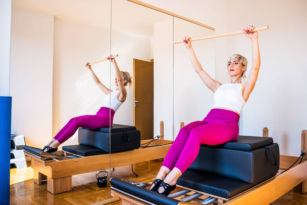 Woman is exercising on pilates reformer bed at home. - Photo, Image