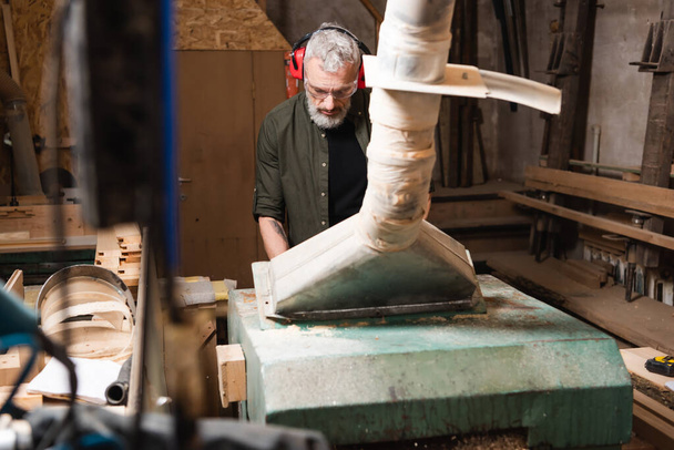 carpintero barbudo que trabaja cerca de la campana de ventilación en primer plano borroso - Foto, Imagen