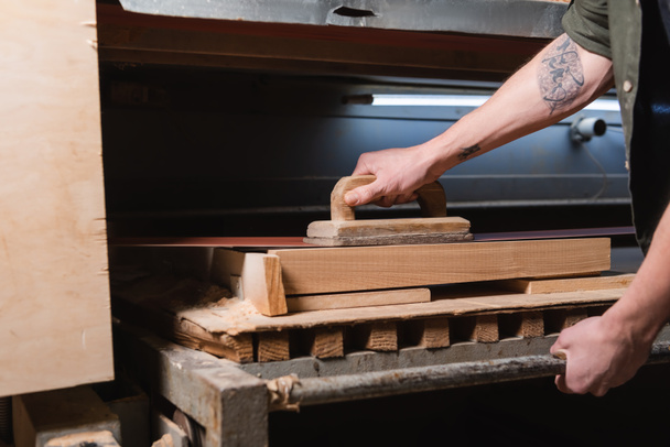 καλλιεργημένη άποψη του ξυλουργού με τατουάζ στίλβωση ξύλου σε μηχανή τριβής - Φωτογραφία, εικόνα