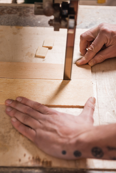 vista recortada de carpintero de corte de madera contrachapada con sierra de banda  - Foto, imagen