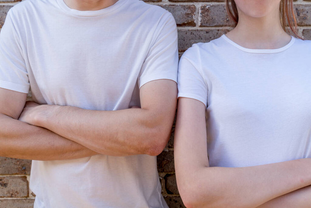 Couple wearing mockup white t-shirts on brick wall background holding hands. Template copy space fashion - Fotoğraf, Görsel