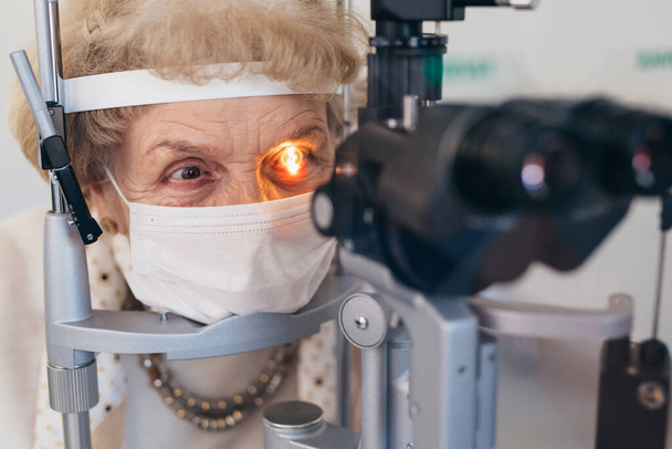 close up of senior woman has eye examination. coronavirus concept - Foto, afbeelding