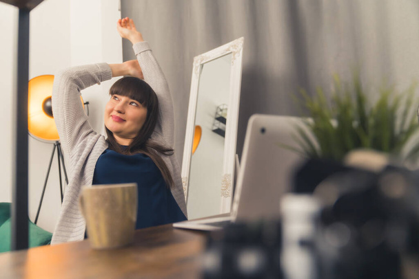 Beautiful cheerful European woman sitting in front of her computer, stretching and relaxing. Leisure time activity concept.  - Photo, image