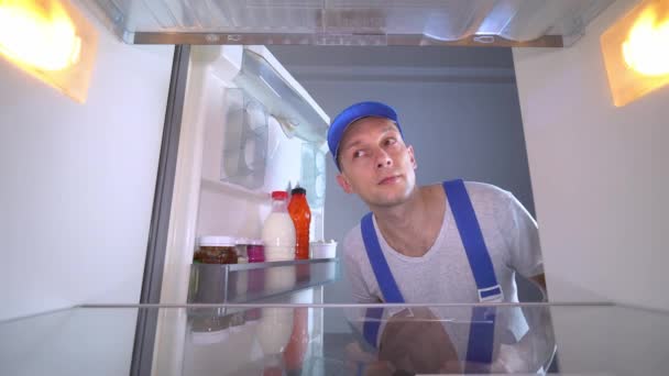 De koelkast reparateur opent de deur en de lijst van werken - Video