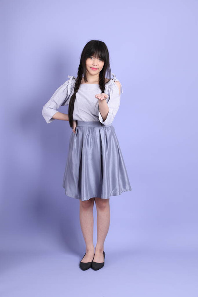 The young Asian girl in purple preppy dressed standing on the purple background. - Foto, Imagen