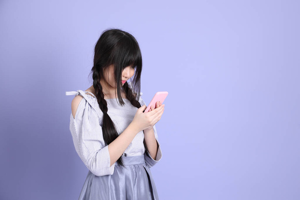 Mladý asijské dívka v fialové preppy oblečený stojící na fialovém pozadí. - Fotografie, Obrázek