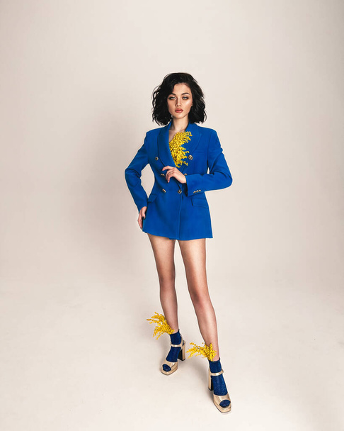 Young girl with dark hair in a blue jacket and sandals in gold and mimosa - Foto, imagen