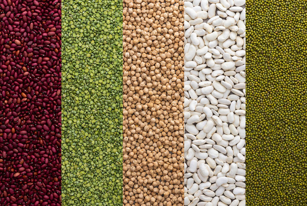Diferentes tipos de legumbres, garbanzos y frijoles mungo, frijoles blancos y rojos y guisantes verdes, vista superior - Foto, imagen