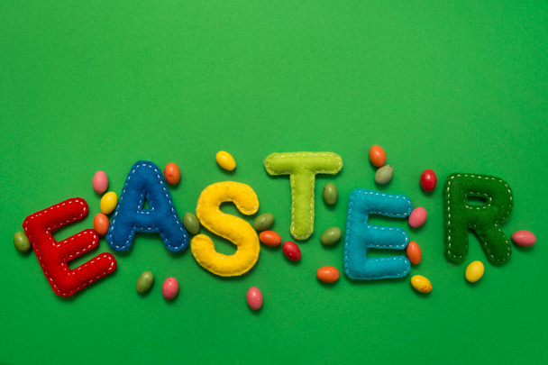 Handmade stuffed colorful felt letters on a green background. The concept of Easter. Minimalist creative. Poster or greeting card. - Zdjęcie, obraz