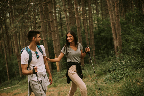 Un par de jóvenes excursionistas con mochilas caminan por el bosque - Foto, imagen