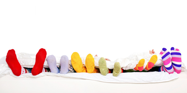 Щаслива сім'я в барвистих шкарпетках на білому ліжку
. - Фото, зображення