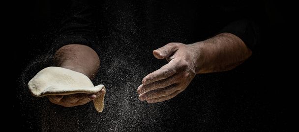 Розгорніть руки пекаря з борошном. Красиві і сильні чоловічі руки замішують тісто, щоб зробити хліб, макарони або піцу. Порошкове борошно літає в повітря
. - Фото, зображення