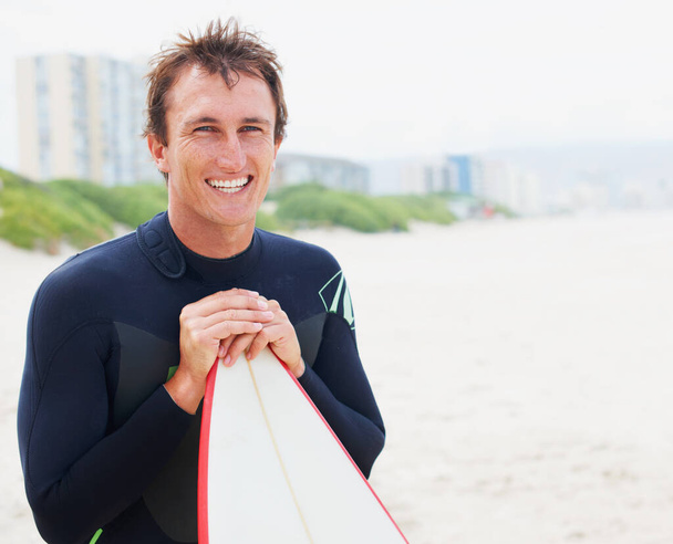 Ik voel me geweldig na een epische sessie. Een surfer poseert op het strand met zijn board naast copyspace. - Foto, afbeelding